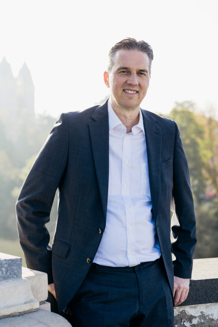 Gunnar Johannen steht im Freien, im Hintergrund sieht man noch einzelne Türme eines Schlosses.